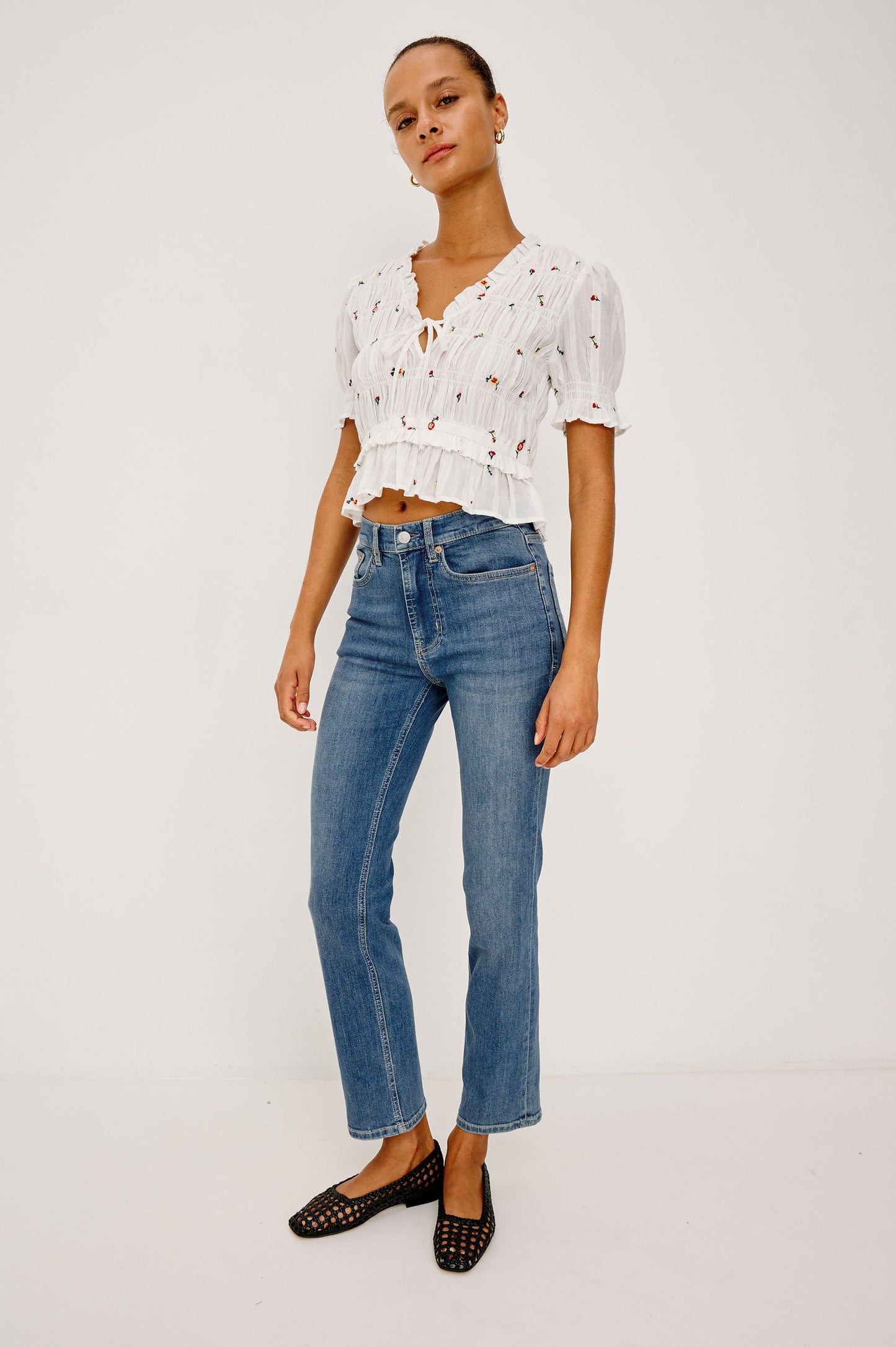 Woman wearing a white floral top and blue jeans 