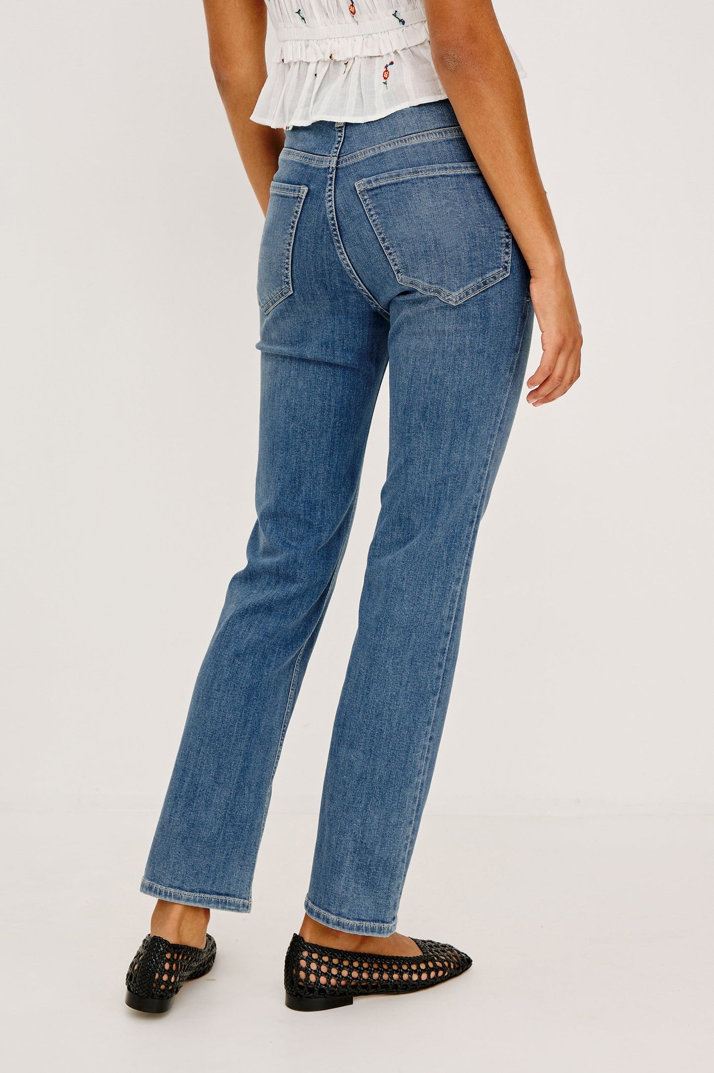 Woman wearing a white floral top and blue jeans 