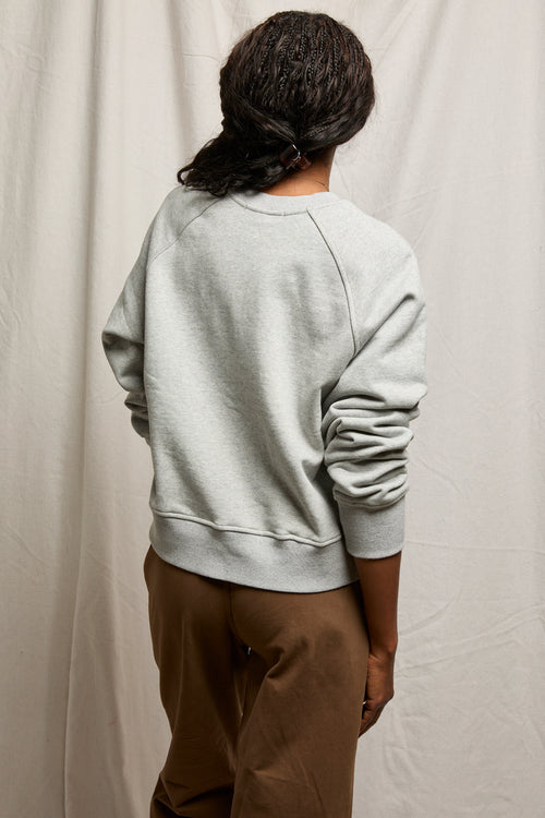 Individual facing away in gray sweatshirt and brown pants, shown against a plain background for casual wear context.