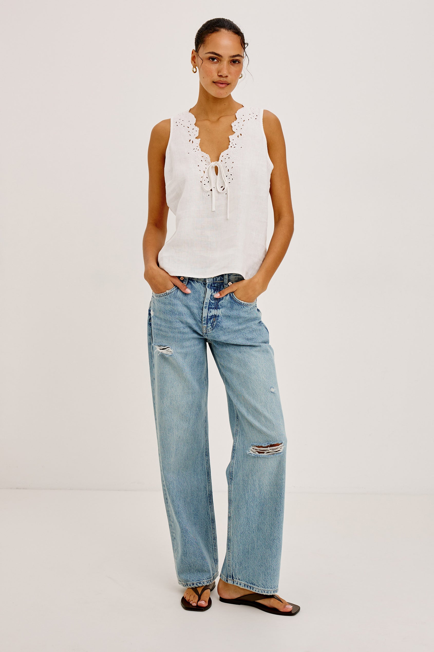 Woman wearing a white sleeveless top with lace details 