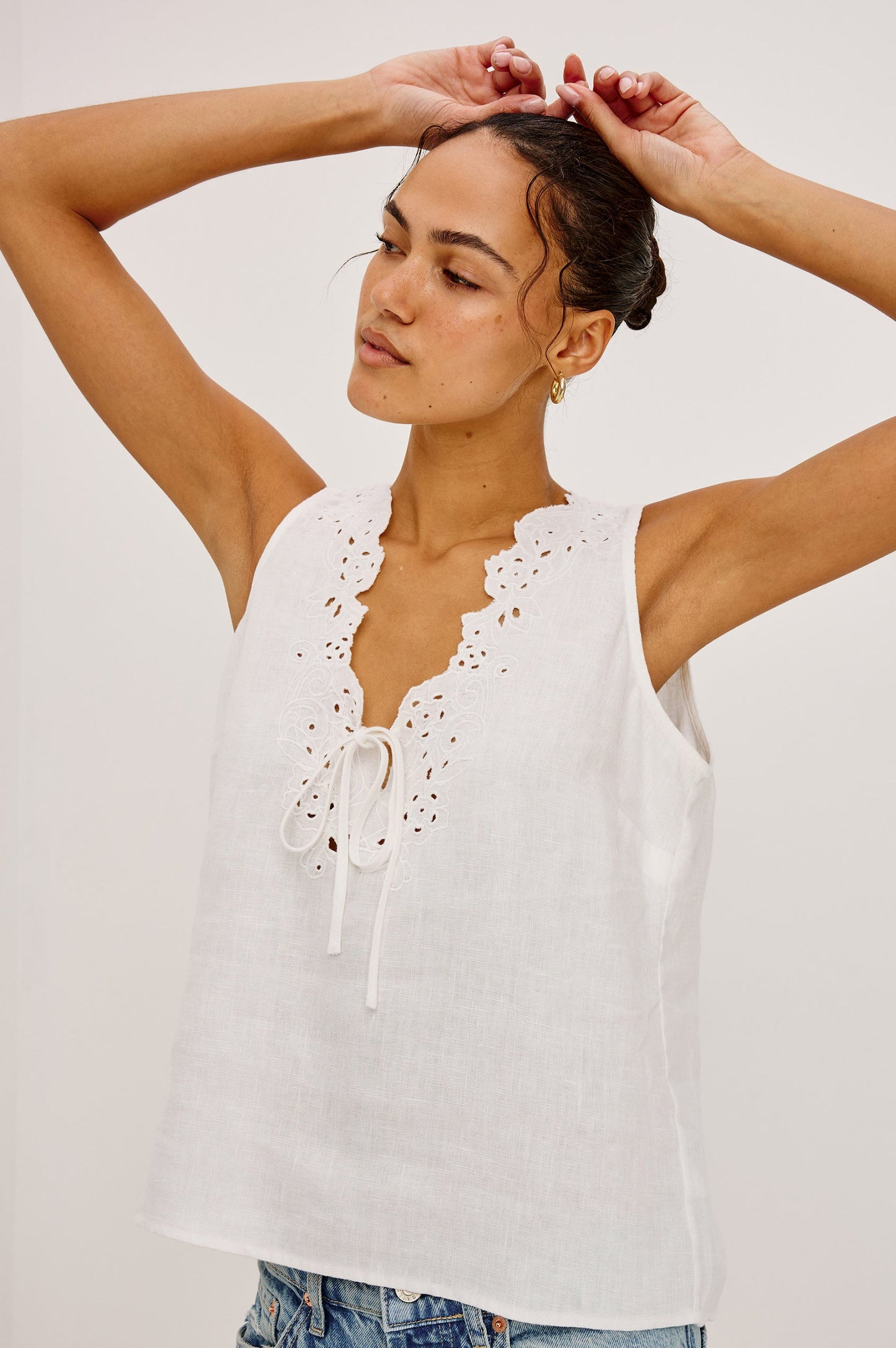 Woman wearing a white sleeveless top with lace details 