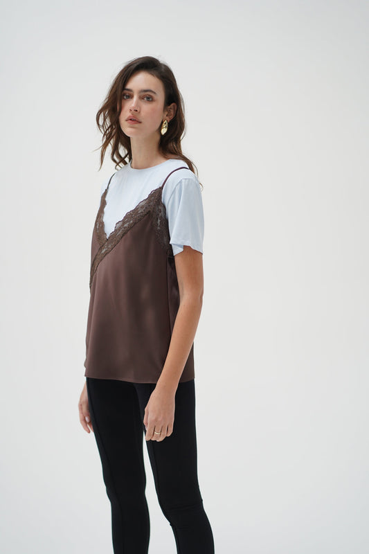 Woman wears a cacao and 90′s blue cami layer tee with black pants and gold earrings.