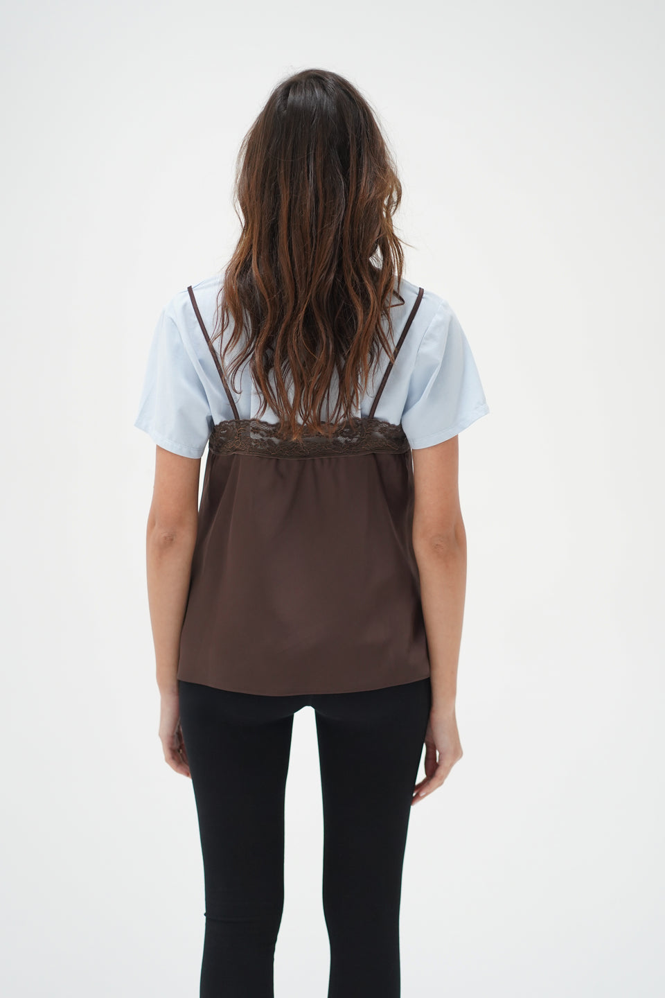 Woman with wavy brown hair wears a cacao and blue cami layer tee, shown from the back for casual wear.