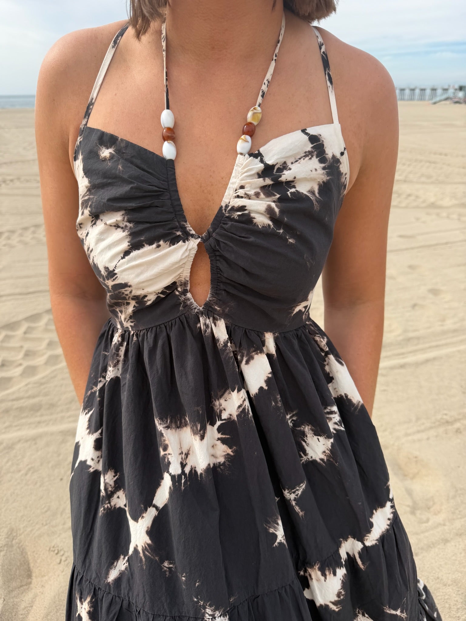 Woman on the beach wearing a light-colored poplin dress, ideal for casual summer wear.