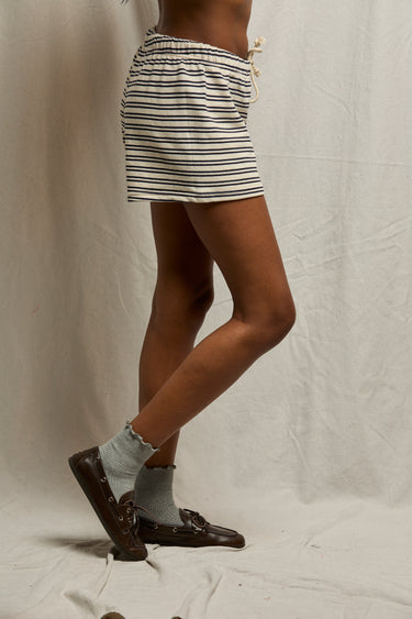 Navy striped cotton shorts, gray socks, and brown loafers set against an off-white background.