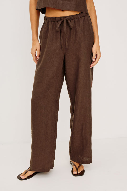 Woman in espresso-colored drawstring pants and matching crop top, paired with black sandals. Suitable for casual wear.