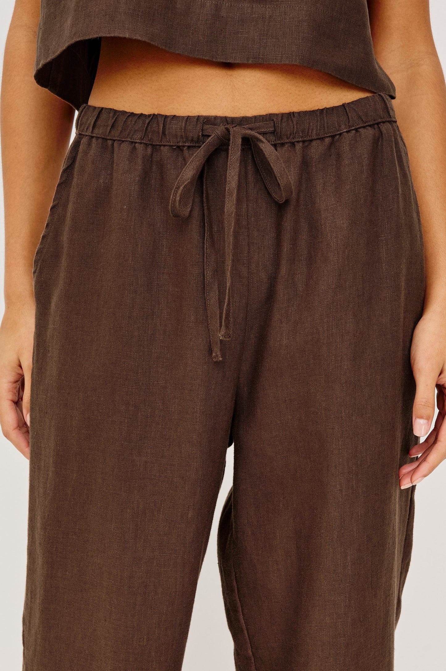 Espresso-colored high-rise pants with adjustable drawstring waist, shown from waist to mid-thigh.