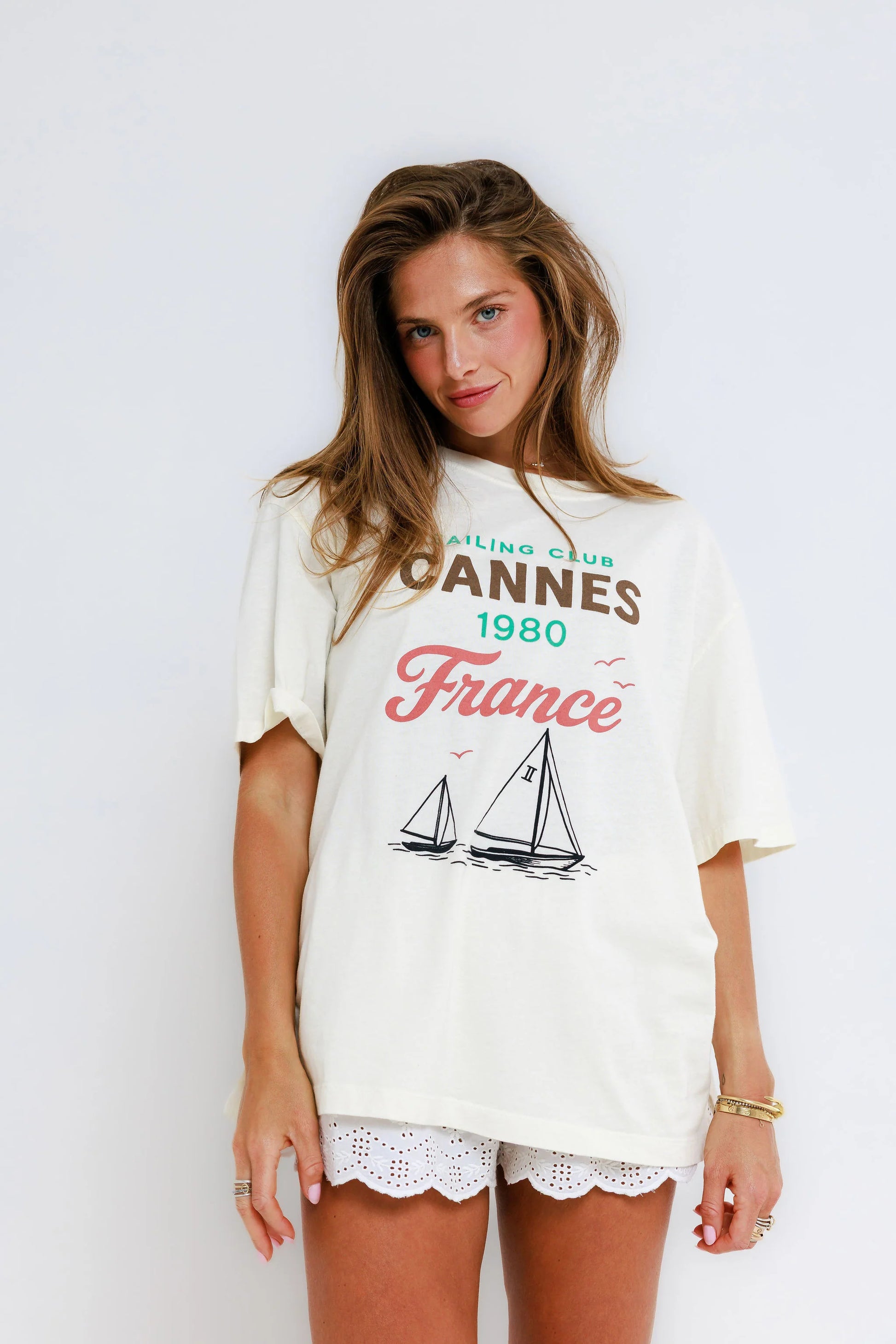 Woman in off-white everyday tee and white eyelet shorts stands against a plain white background.