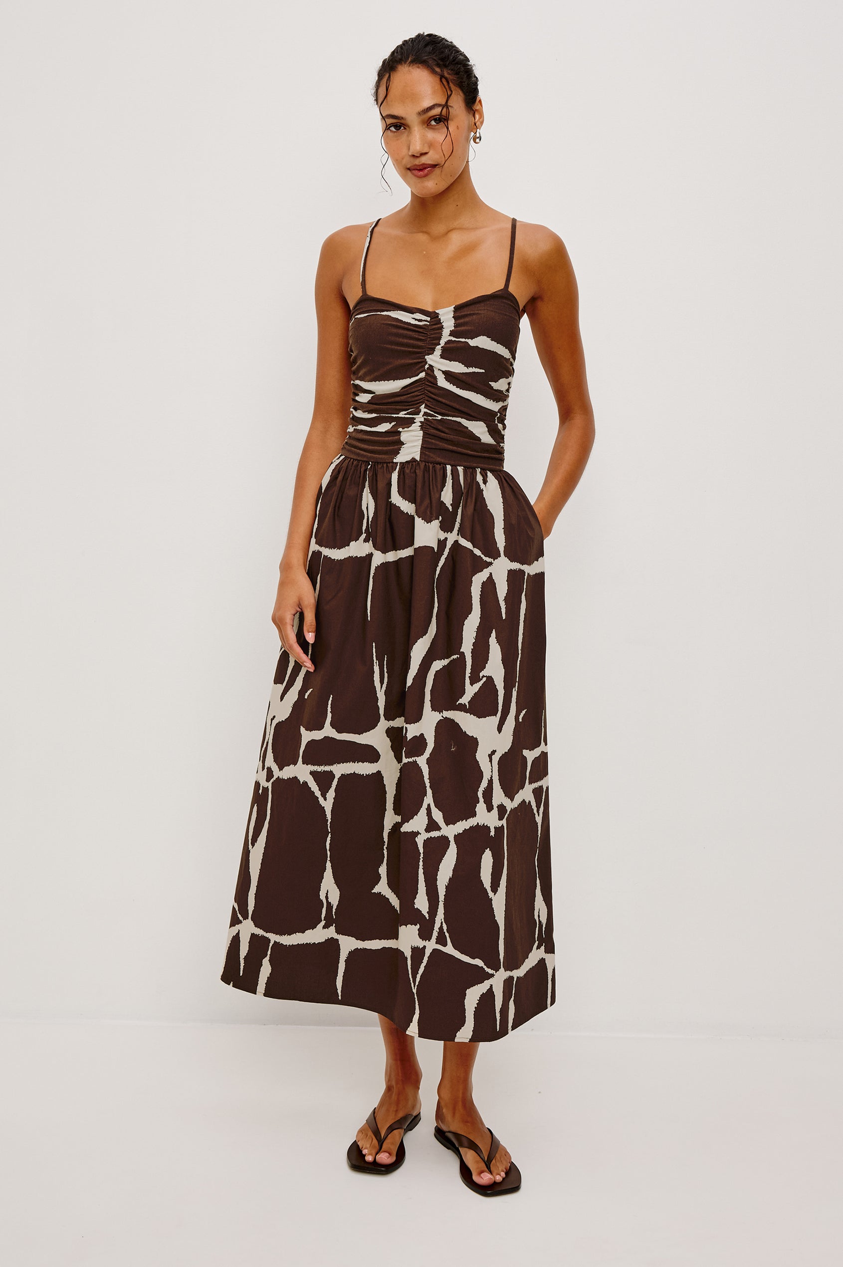 Brown and white abstract maxi dress with adjustable straps, shown on a woman against a white background.
