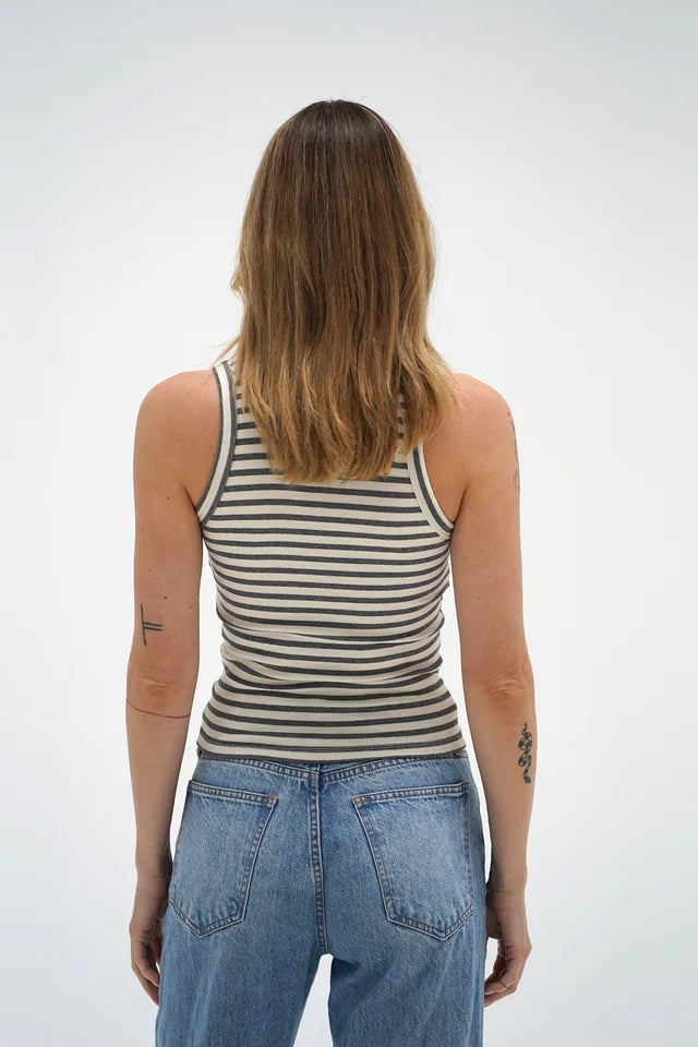 Person seen from behind in a striped greyscale tank top and blue jeans, highlighting the tanks color and cut.