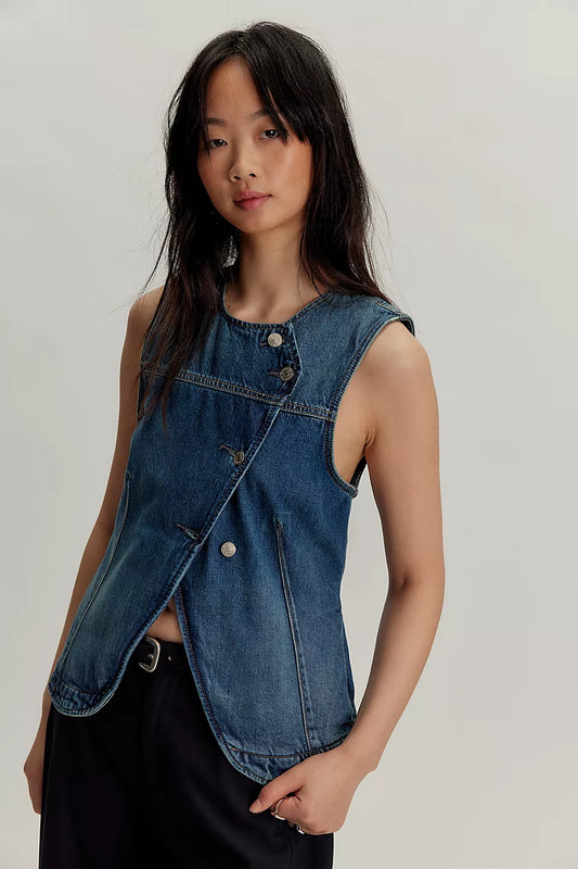 Woman in light denim vest and black pants stands against a plain background. Vest features sturdy cotton fabric and metal buttons.