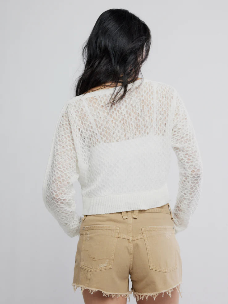 Woman with long dark hair wears a fine-gauge ivory cardigan, shown from the back.