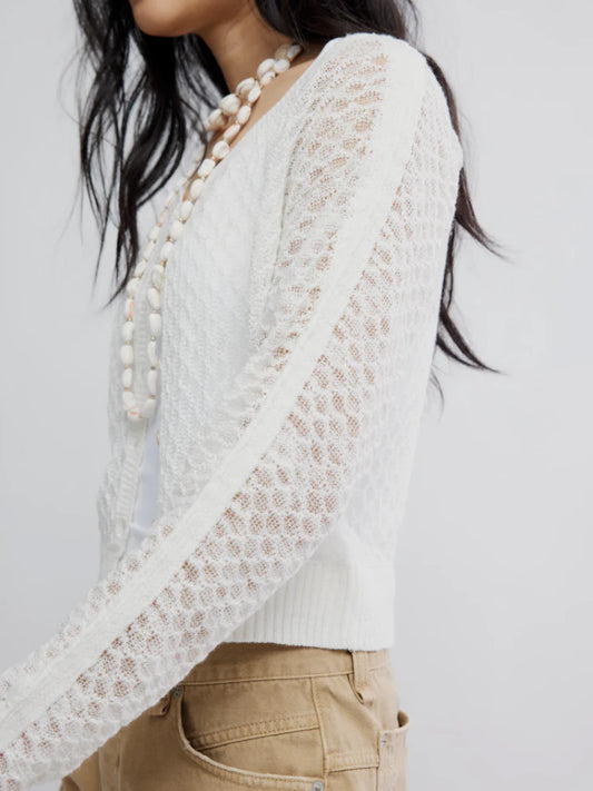 Woman in ivory fine gauge cardigan, beige pants, and a long beaded necklace. Sweater looks soft and lightweight.