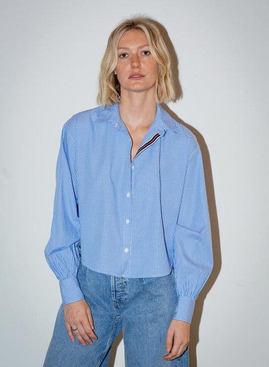 Blue and white pinstripe cotton button-up shirt paired with jeans, shown on a model against a plain white background.
