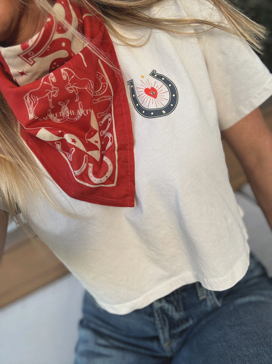 Individual in a patterned bandana and white cotton t-shirt with a horseshoe graphic, shown from the shoulders up.