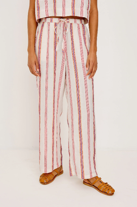 Woman in striped cotton pants and matching top with tan sandals, standing indoors. Outfit suited for casual wear.