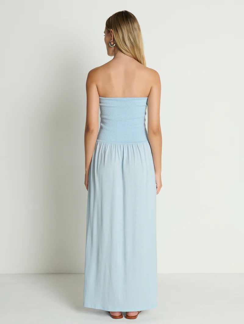 Back view of strapless sky blue tube dress with smocked bodice, shown on plain white background.