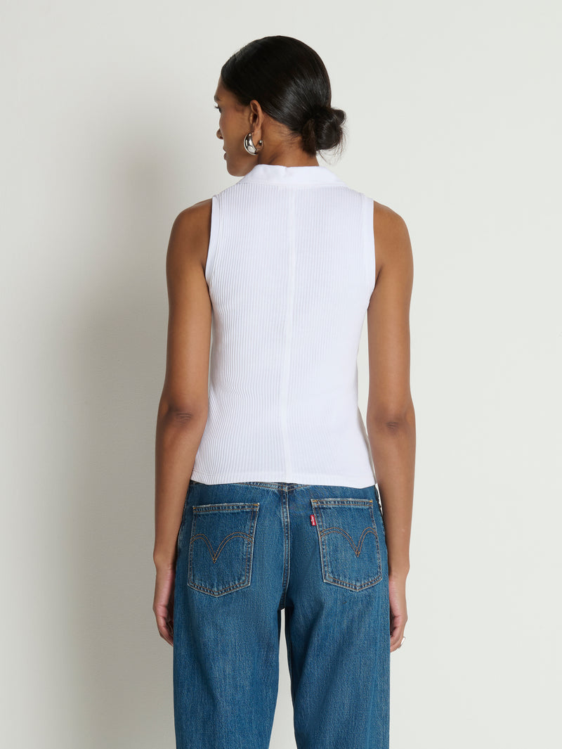 Person wearing a white sleeveless top and blue jeans