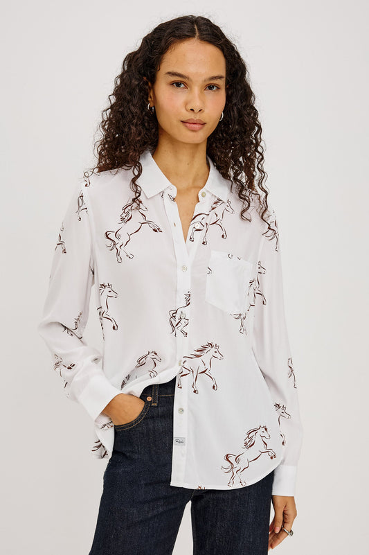 A woman wearing a white long-sleeve button-up shirt with an allover embroidered horse pattern