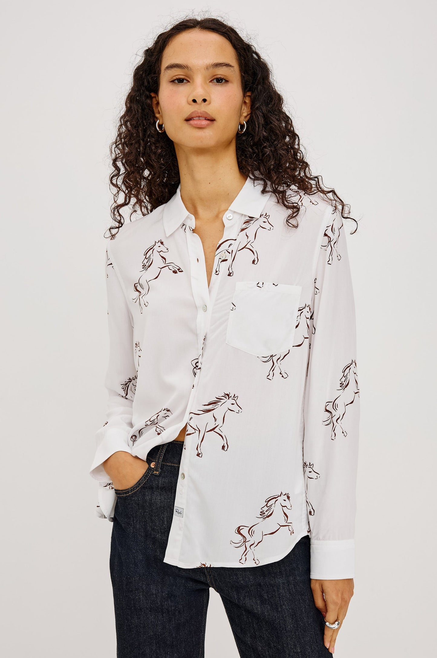 A woman wearing a white long-sleeve button-up shirt with an allover embroidered horse pattern