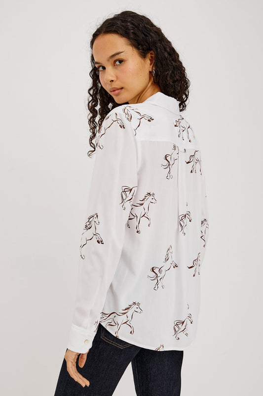 A woman wearing a white long-sleeve button-up shirt with an allover embroidered horse pattern
