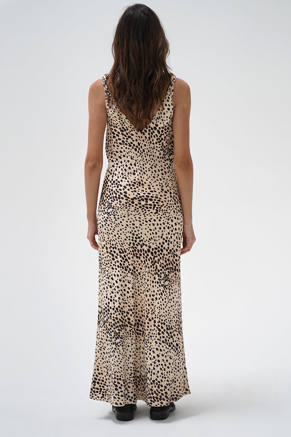 A woman modeling a sleeveless V-neck maxi dress with a beige and black leopard print pattern