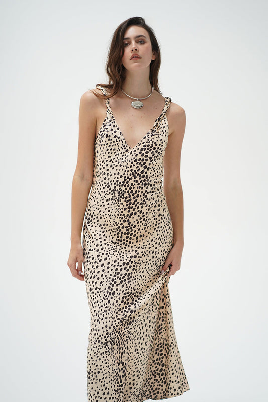A woman modeling a sleeveless V-neck maxi dress with a beige and black leopard print pattern
