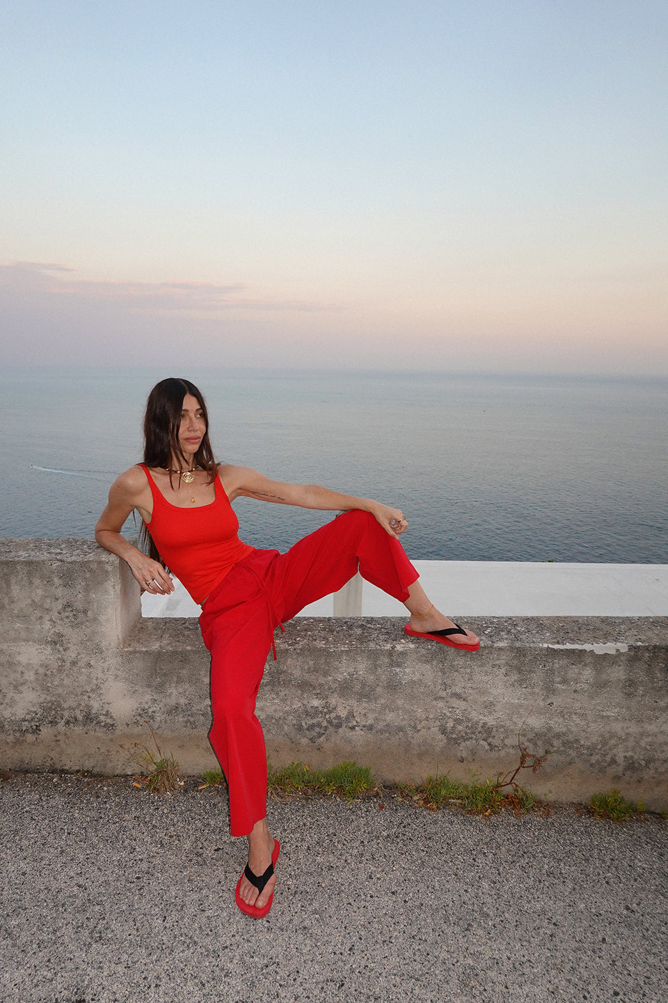 A woman wearing bright red wide-leg drawstring pants and a matching red top