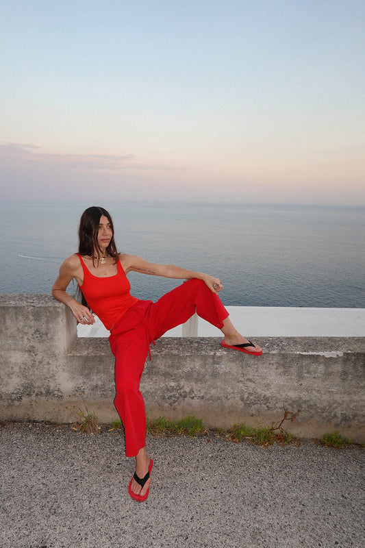 A woman wearing bright red wide-leg drawstring pants and a matching red top