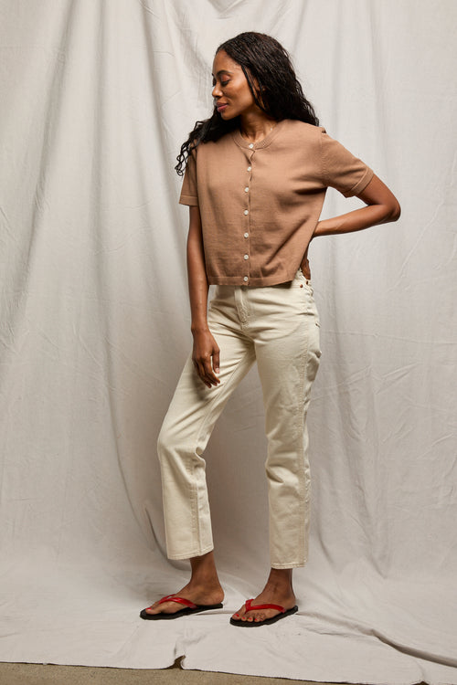 Woman wears a mocha-colored knit cardigan on a white background, facing left.