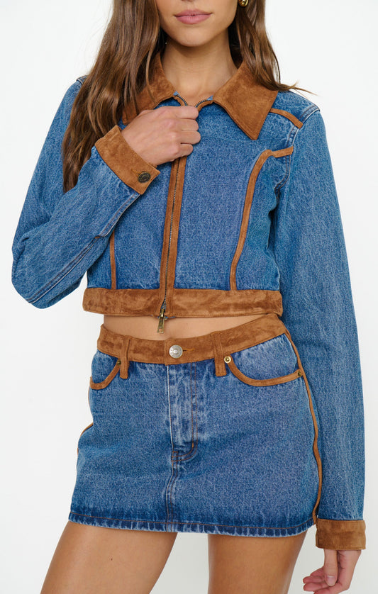 Person wearing a blue denim Western jacket with faux suede trim and gold zipper, suitable for casual or outdoor use.