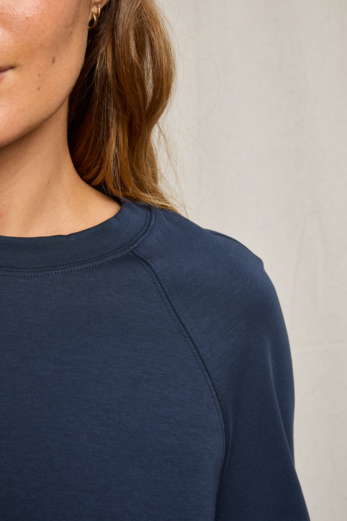 Woman wearing a navy crew neck sweatshirt made from lightweight, travel-friendly fabric.