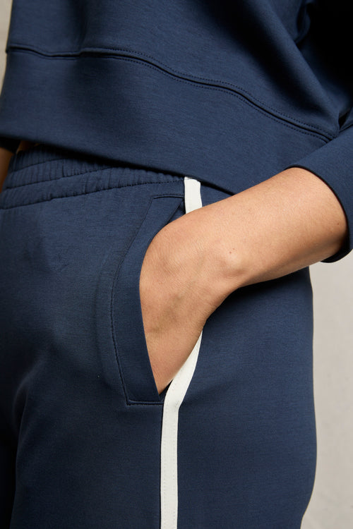 Person wears navy wide-leg cotton pants and a matching sweatshirt, one hand in pocket.