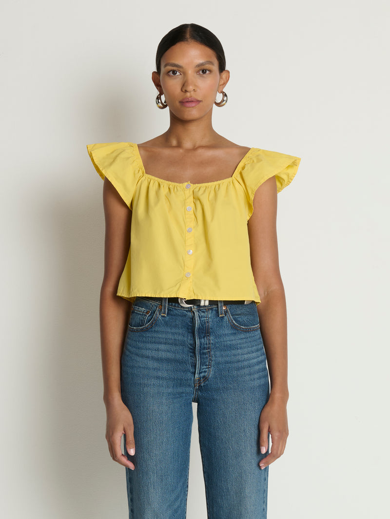 Woman wearing a yellow top with ruffled sleeves 