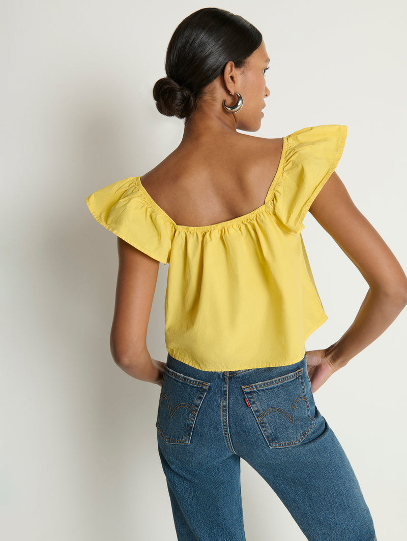 Woman wearing a yellow top with ruffled sleeves 