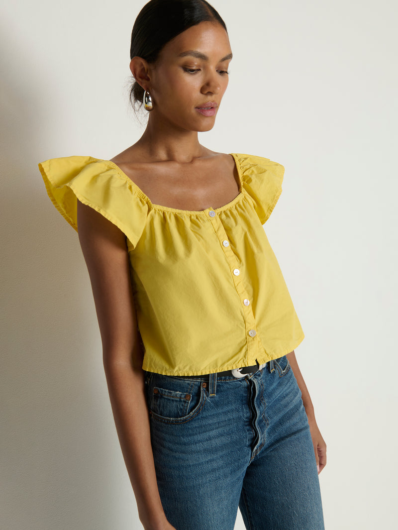 Woman wearing a yellow top with ruffled sleeves 