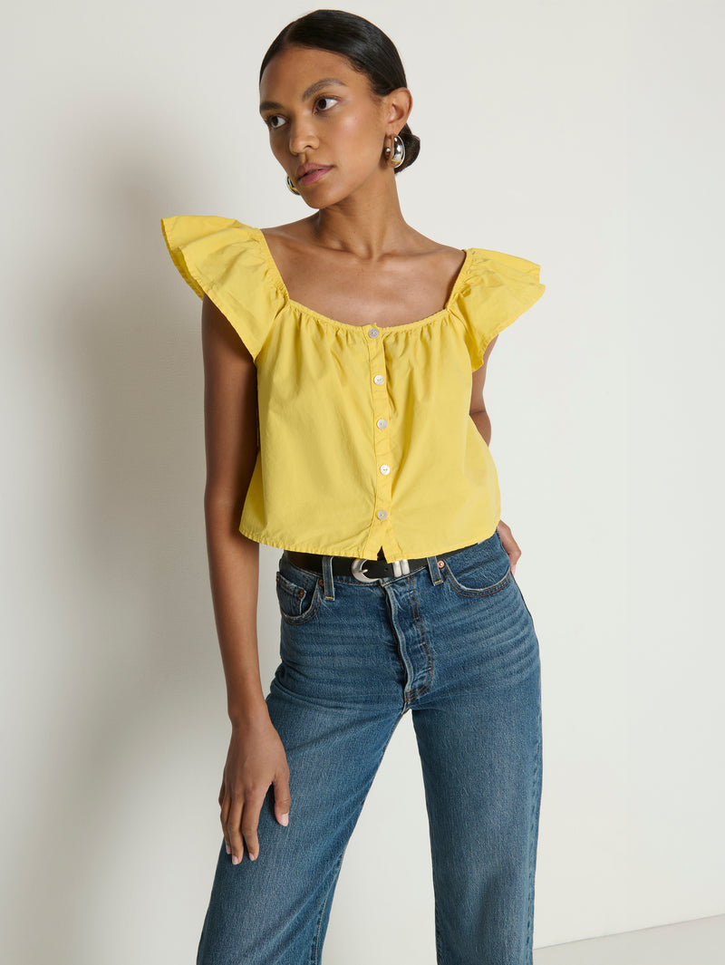 Woman wearing a yellow top with ruffled sleeves 