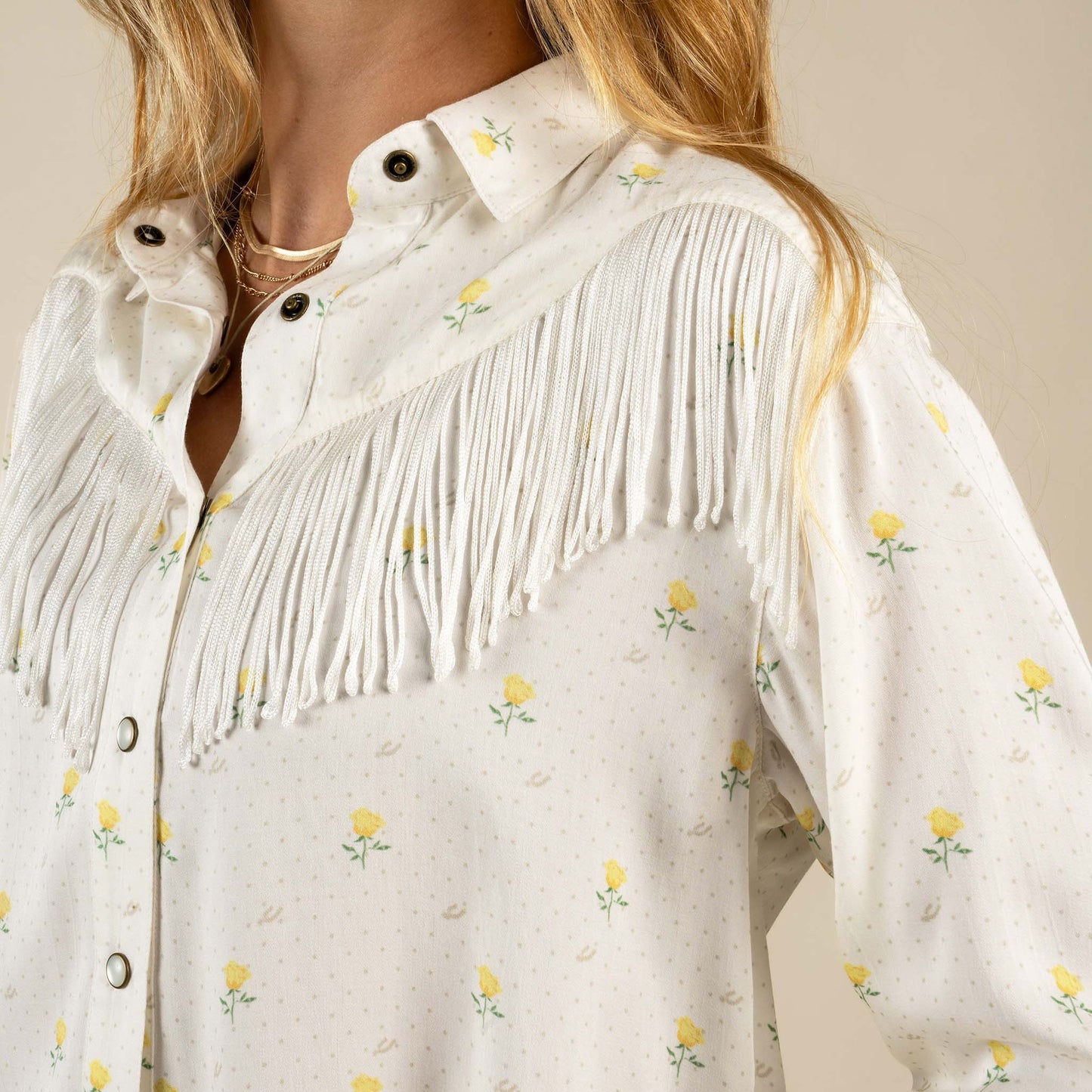 Woman wearing a white blouse with fringe details 