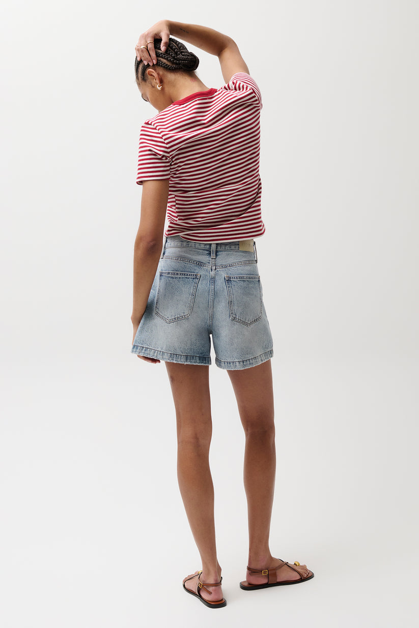 Person in denim Saige shorts, French Riviera wash, and red striped shirt faces away with hand on head.