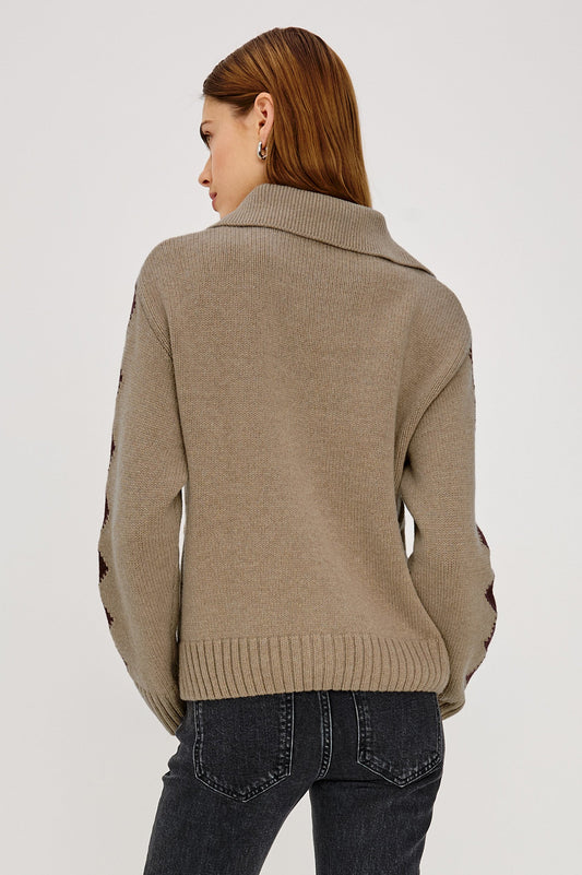 Woman wearing a beige sweater with horse shoe designs