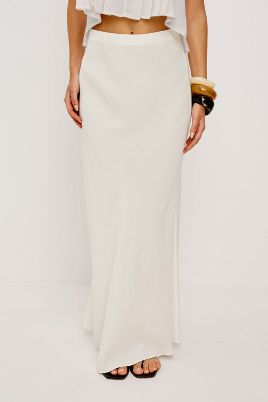 Ivory midi skirt paired with a cropped white top, black sandals, and chunky bracelets, ideal for casual outings.