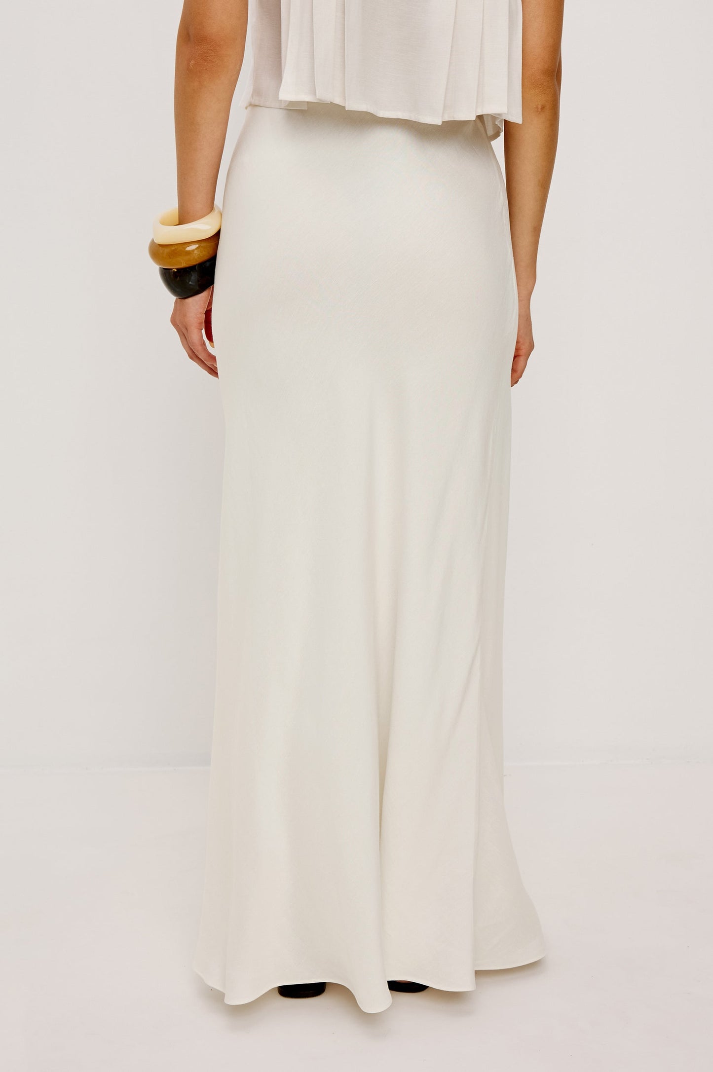 Ivory midi skirt in lightweight fabric, styled with a sleeveless top and chunky bangles against a plain background.