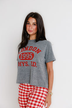 Woman with long dark hair wears a white cotton crewneck sweatshirt, standing in front of a white wall.