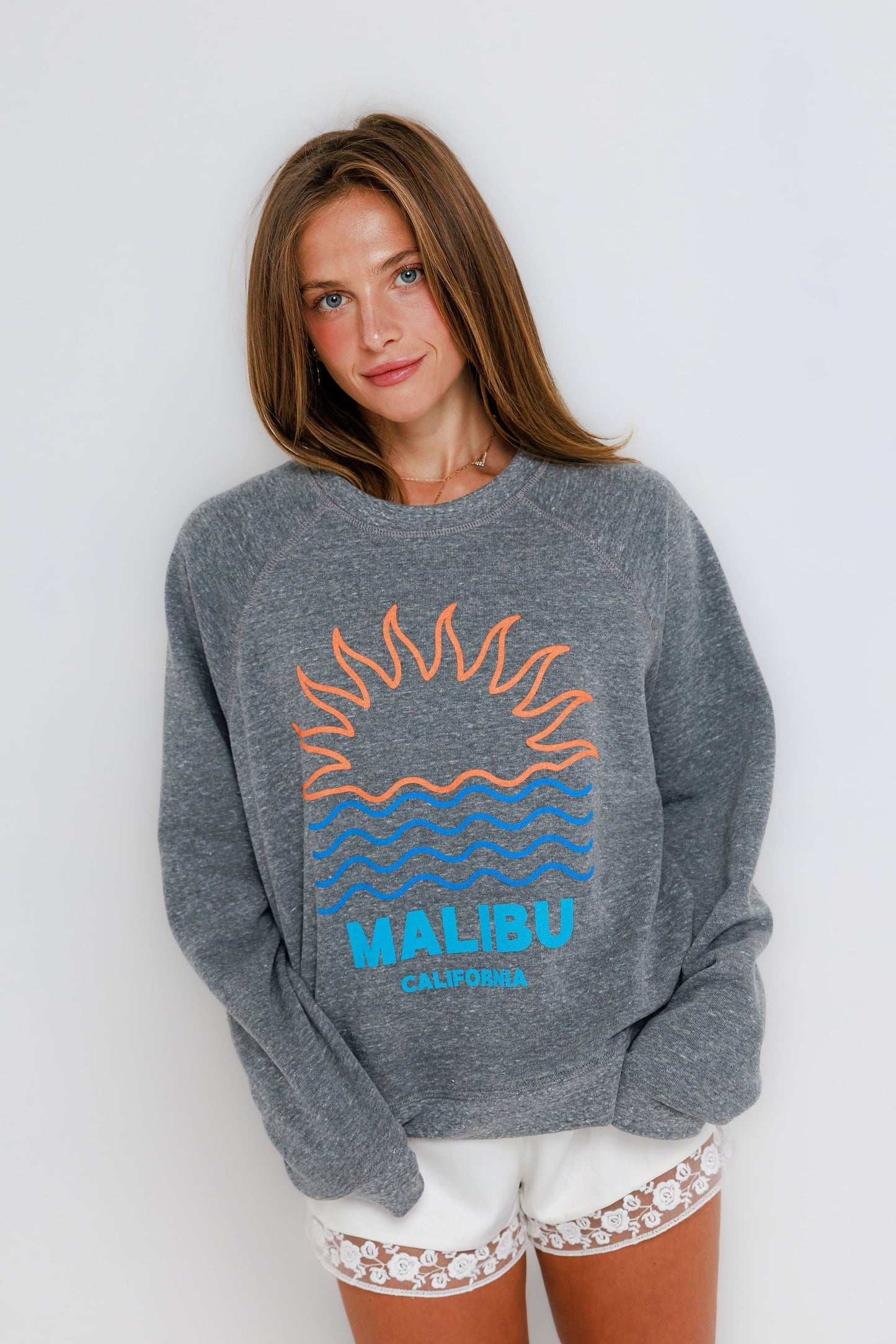 Gray raglan crewneck sweatshirt with white lace-trim shorts, shown on woman standing against a plain background.