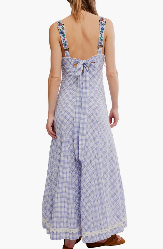 Back view of a woman in a white patterned maxi dress with a flowy fit, suitable for summer or casual occasions.