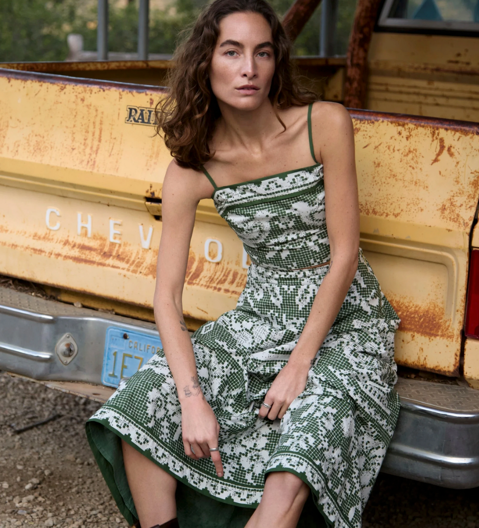 Woman in a green printed ankle skirt sits on a yellow vintage Chevrolet pickup truck, highlighting skirts light, flowing fabric.