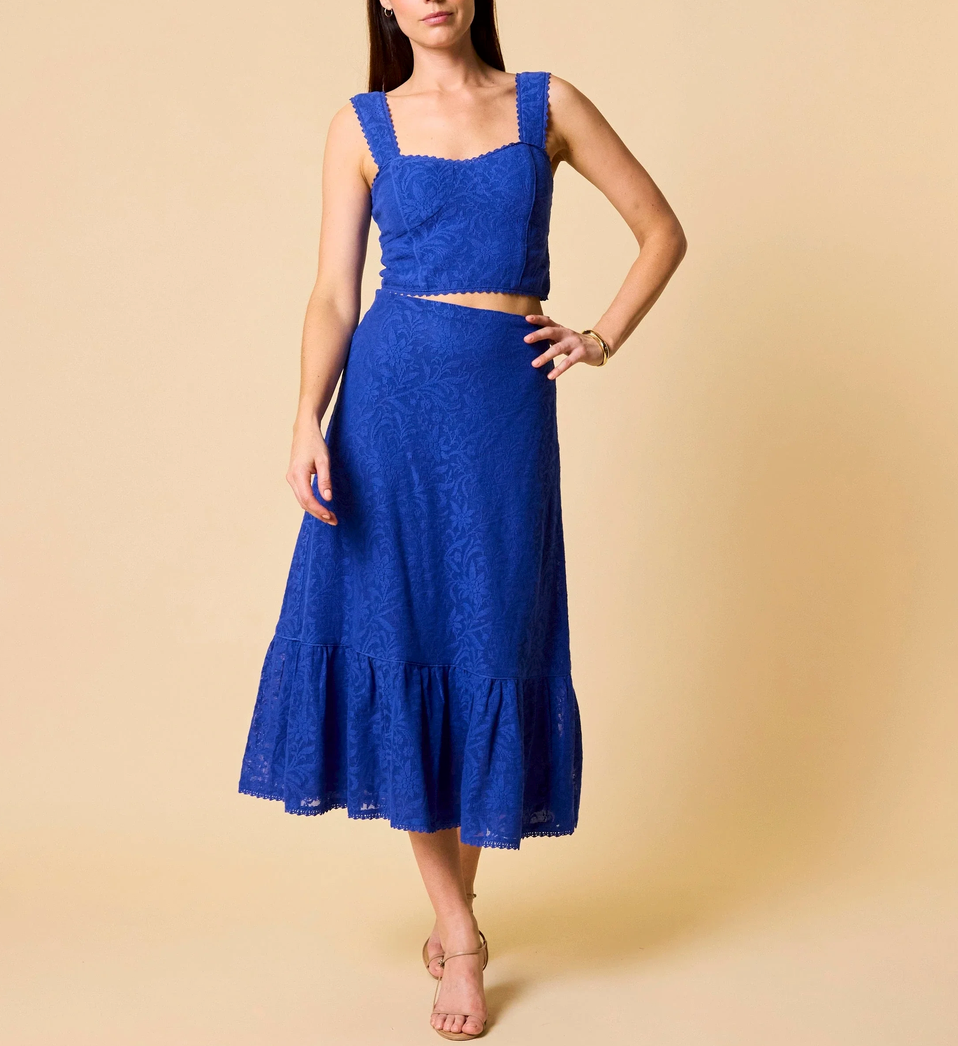 A woman models a royal blue lace top with matching skirt