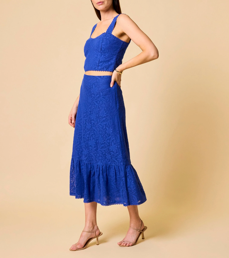A woman models a royal blue lace top with matching skirt