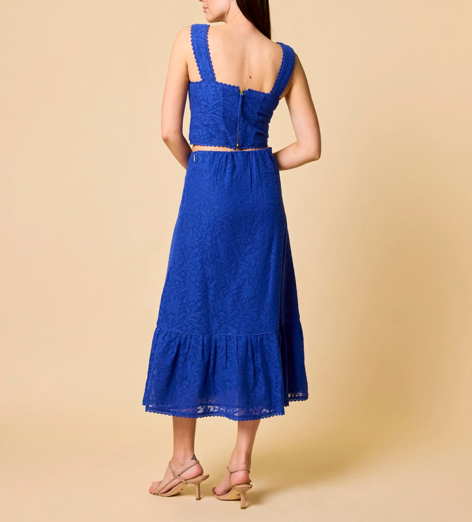 A woman models a royal blue lace top with matching skirt