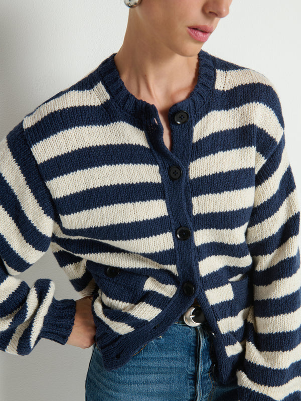 Woman in a striped blue and white cardigan with blue jeans, showcasing a casual knitwear look.